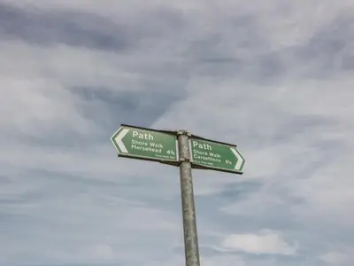 a street sign with two green street signs on a pole at Wagtail Cottage in Mainsriddle