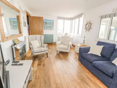 a living room with a blue couch and chairs at Wagtail Cottage in Mainsriddle