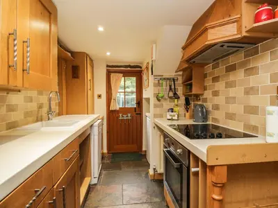 a kitchen with wooden cabinets and a stove top oven at The Cottage at Graysondale Farm in Cockermouth