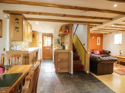 a kitchen and living room with a couch and stairs at The Cottage at Graysondale Farm in Cockermouth