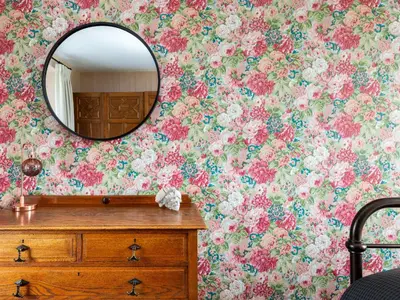 a bathroom with a flowery wallpaper and a mirror at Stag Cottage in Penrith