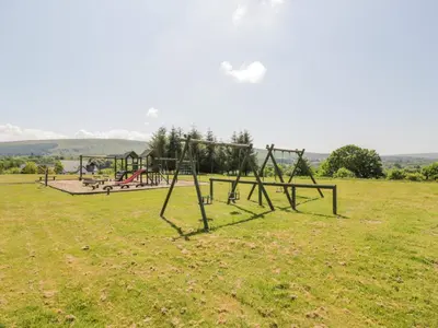 an empty park with an empty swing set in a field at Brunston Castle Lodge in Girvan
