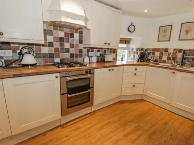 a kitchen with white cabinets and a stove top oven at Rowan Cottage in Grasmere