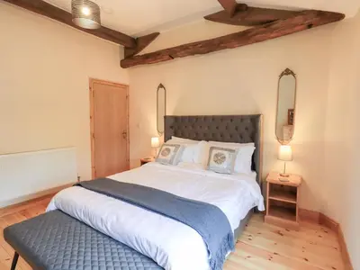 a bedroom with a large bed with a blue blanket at Rose Cottage in Crosby