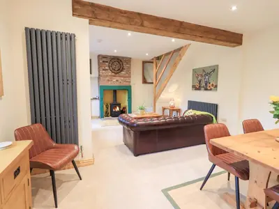 a living room with a leather couch and a table and chairs at Rose Cottage in Crosby
