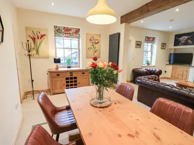 a living room with a table with a vase of flowers on it at Rose Cottage in Crosby