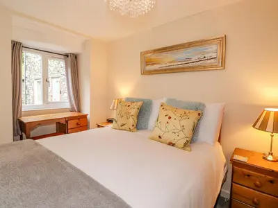 a bedroom with a white bed and a window at Maple Cottage in Keswick