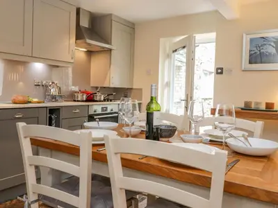 a kitchen with a dining room table with wine glasses at Maple Cottage in Keswick