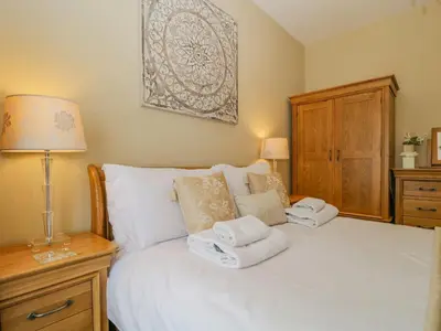 a bedroom with a white bed with towels on it at Garden Cottage in Keswick