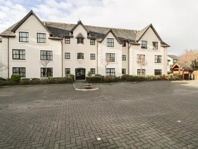 a large white building with a brick parking lot at Andra Ghyll in Keswick