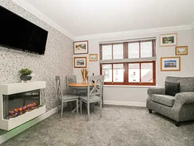 a living room with a fireplace and a table and chairs at Andra Ghyll in Keswick