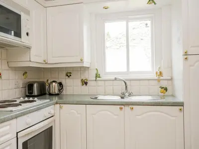a kitchen with white cabinets and a sink and a window at Thirlmere Suite in Thirlmere