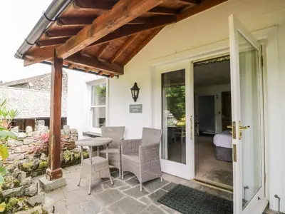 a patio with a table and chairs next to a stone wall at Thirlmere Suite in Thirlmere