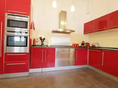 a kitchen with red cabinets and stainless steel appliances at Keswick Loft in Keswick