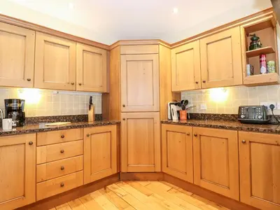 a kitchen with wooden cabinets and a wooden floor at How End in Braithwaite