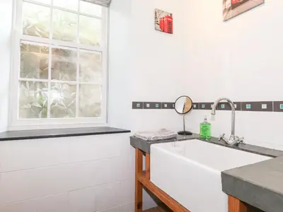 a white kitchen with a sink and a window at How End in Braithwaite