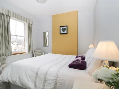 a bedroom with a large white bed and a window at Banks Place in Keswick