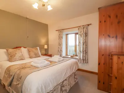 a bedroom with a large bed and a window at Low Garth Cottage in Penruddock