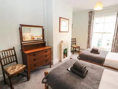a bedroom with two beds and a mirror and a dresser at Pelham House in Keswick