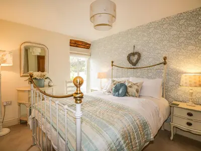 a bedroom with a bed and a mirror at Stockwell Hall Cottage in Sebergham