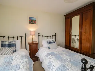 a bedroom with two beds and a mirror at Stockwell Hall Cottage in Sebergham