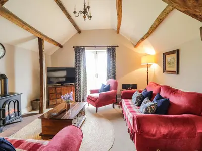 a living room with red furniture and a fireplace at Stockwell Hall Cottage in Sebergham