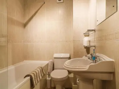 a bathroom with a toilet and a sink and a tub at Siskin in Keswick