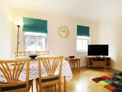 a dining room with a table and a television at Fox's Den in Keswick