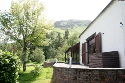 a white house with a brick wall and a window at The Byre in Keswick