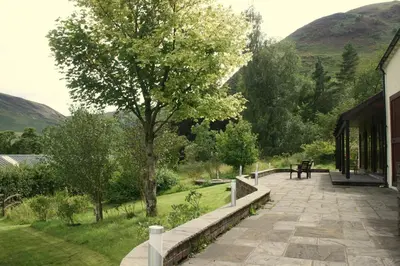 a patio with a tree and a bench next to a building at The Byre in Keswick