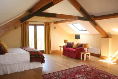 a bedroom with a bed and a red chair at The Byre in Keswick