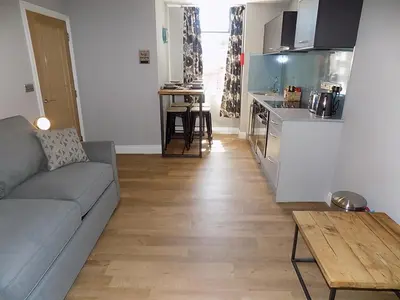 a living room with a couch and a kitchen at The Old Wool House Apartments in Carlisle