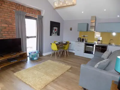 a living room with a gray couch and a kitchen at The Old Wool House Apartments in Carlisle