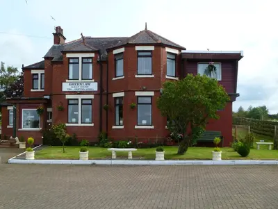 a large red brick building with a sign on it at Greenlaw Guest House in Gretna Green
