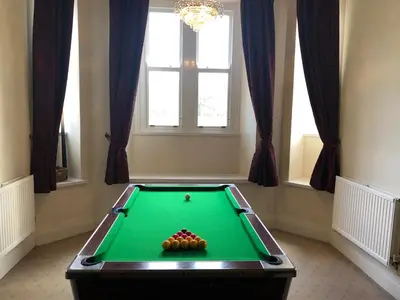 a green pool table in a room with windows at Irton Hall in Eskdale