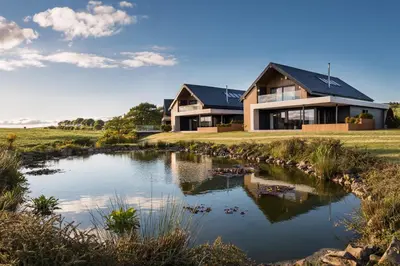 a house with a pond in front of it at Lochside House Hotel & Spa in New Cumnock