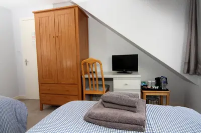 a bedroom with a bed and a desk with a television at Dean Park Guest House in Kilmarnock