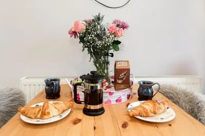 a table with croissants and coffee and a vase of flowers at Jack's Hideaway in Gatehouse of Fleet
