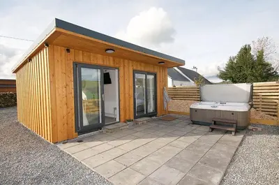 a small wooden building with a hot tub in it at Jack's Hideaway in Gatehouse of Fleet