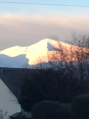 a snow covered mountain with the sun shining on it at Lincoln Guest House in Keswick