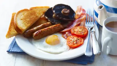 a plate of breakfast food with eggs bacon tomatoes and toast at Woolpack Inn in Eskdale