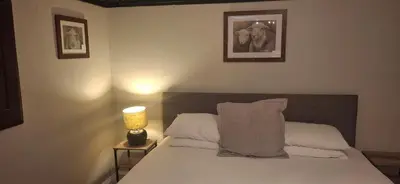 a bedroom with a bed with white sheets and a lamp at Woolpack Inn in Eskdale