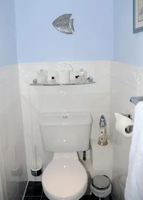 a white bathroom with a toilet and a shelf on the wall at Douglas House in Castle Douglas