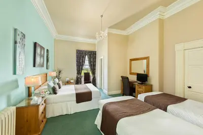 a hotel room with two beds and a desk at The Greenhill Hotel in Wigton