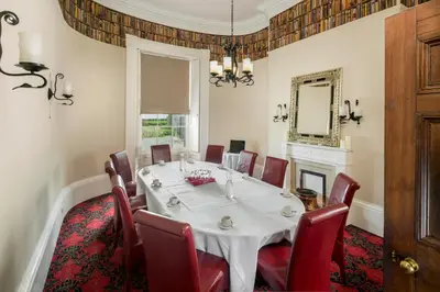 a dining room with a white table and red chairs at The Greenhill Hotel in Wigton