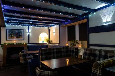 a restaurant with couches and a fireplace and lights at The Crown Hotel in Newton Stewart