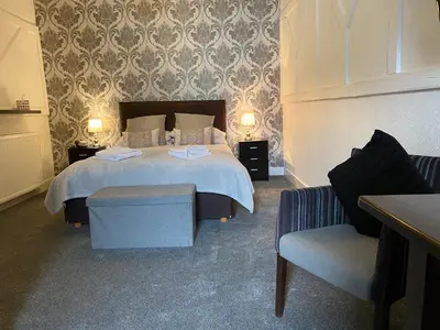 a bedroom with a large bed and a chair at The Crown Hotel in Newton Stewart