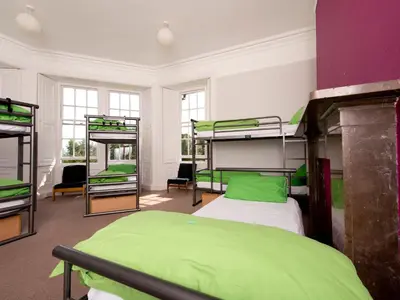 a room with four bunk beds with green sheets at YHA Langdale in Ambleside