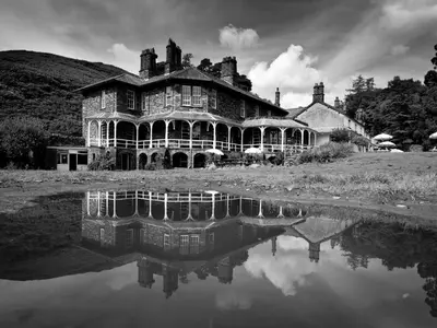 an old house with a reflection in a body of water at YHA Langdale in Ambleside