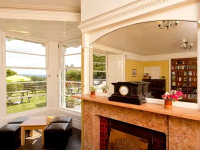 a living room with a fireplace and a large window at YHA Langdale in Ambleside
